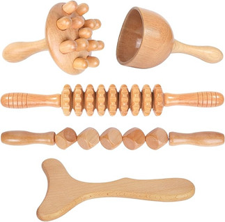 A set of four wooden massage tools by Komogir, each having a unique shape and design, including a spiked ball, a cup, a rolling pin and a handheld tool with a curved end.