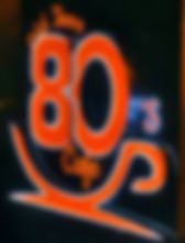 A brightly glowing orange and white neon sign for the "Old Town 80's Cafe" visible at night.