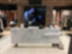 Luxury retail store checkout counter with marble finish, modern vertical slat backdrop, and digital 