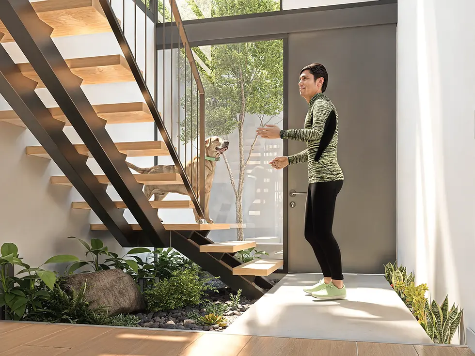 Persona junto a su perro en el interior de una casa 人 HITO, con jardín bajo las escaleras y luz natural.