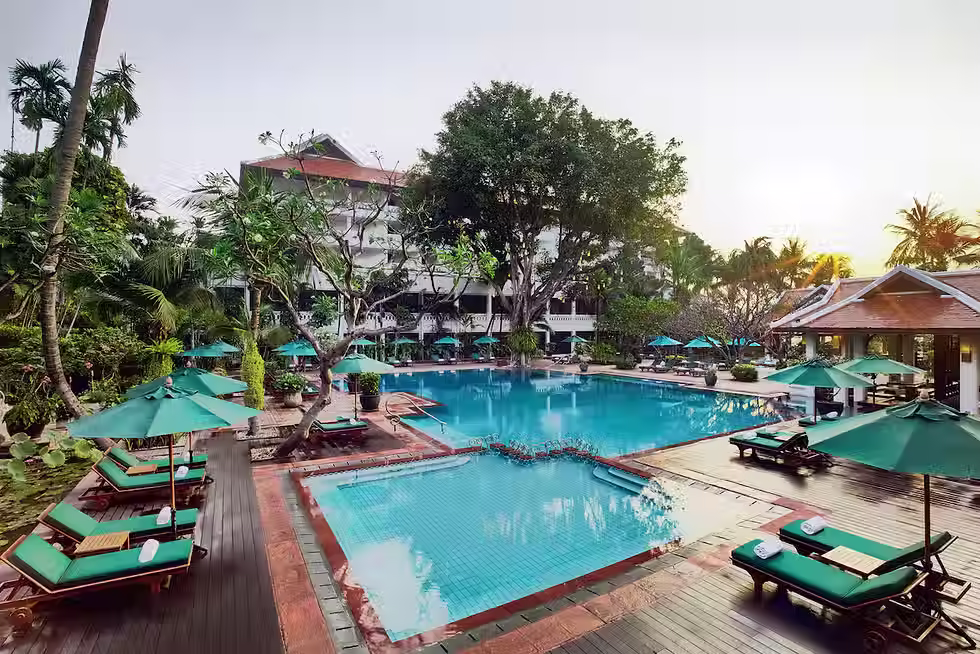 Luxury riverside resort in Bangkok with large swimming pool, tropical gardens, and Chao Phraya River views at Anantara Riverside Bangkok Resort.