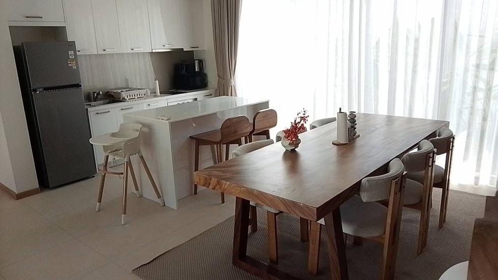 Modern kitchen and dining area with wooden table.