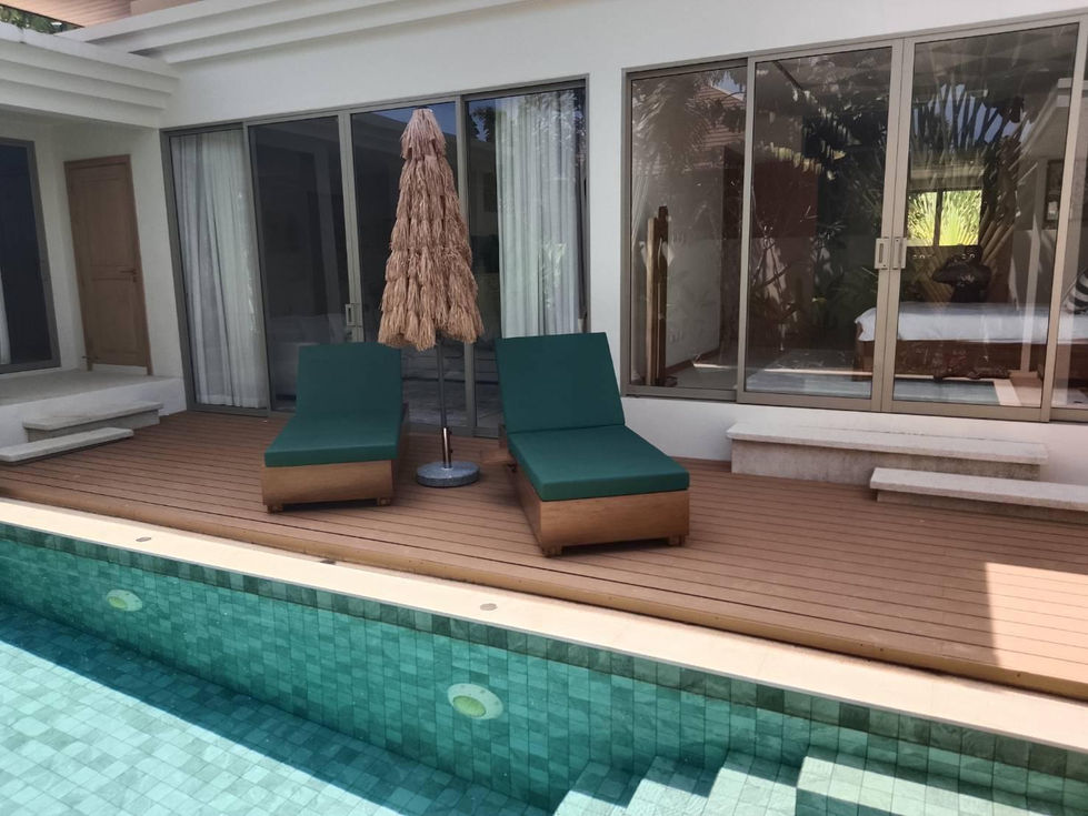 Poolside chairs and umbrella on wooden deck.