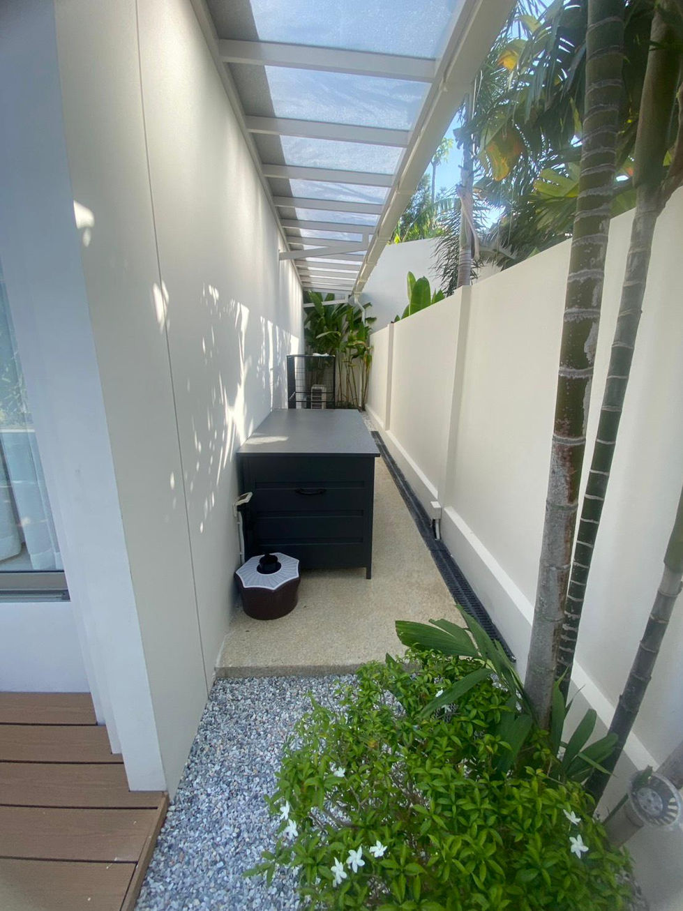 Narrow outdoor space with plants and a covered walkway.