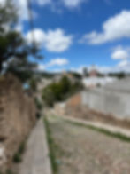 cobblestone street leads to the center of Mineral de Pozos with ancient church in the distance