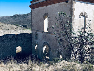 a historic mine building from the 19th century with high desert foliage in the foreground