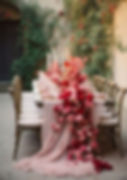Long wedding table with red floral runner and candles