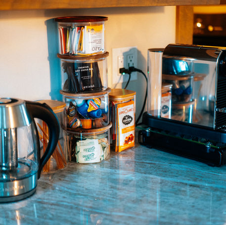 Coffee bar at Haven's Treehouse showing the Nespresso Machine, Tazo tea, Hot chocolate, creamers, sugars, honey straws and a kettle.