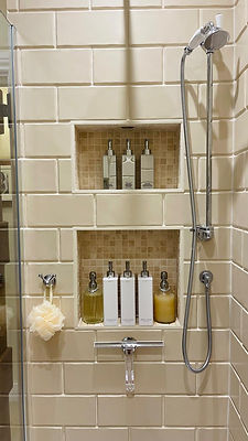 Tiled shower enclosure with built-in wall niche shelf storing toiletries