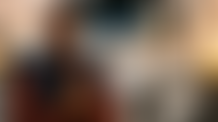 A smiling Black male truck driver stands in front of his white semi truck at sunset with his hands together in a thankful gesture, capturing the gratitude and spirit of Thanksgiving in the trucking industry.