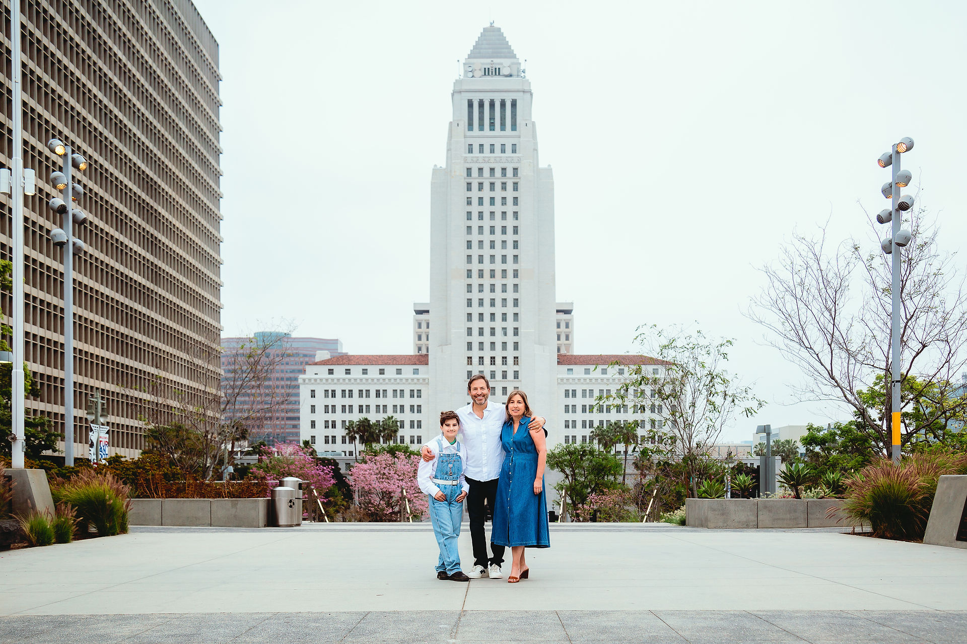 environmental shot of a family of three in an urban area park with Los Angeles City Hall in background