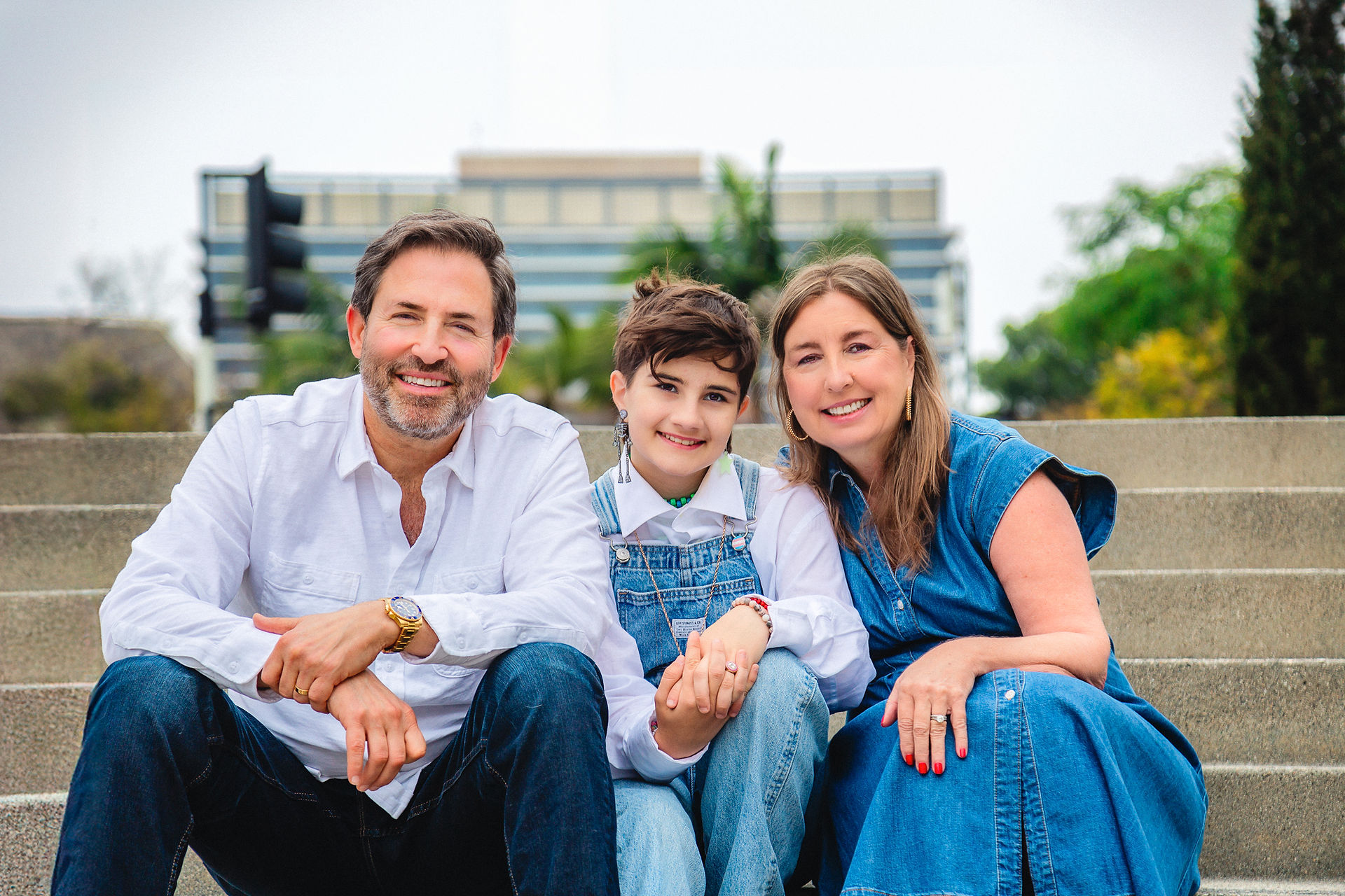 family of three sitting on steps in an urban park