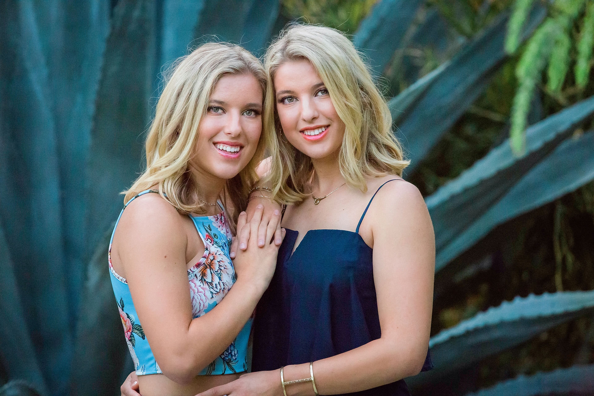 twin sisters in bliue dresses hug each other as they pose for photo