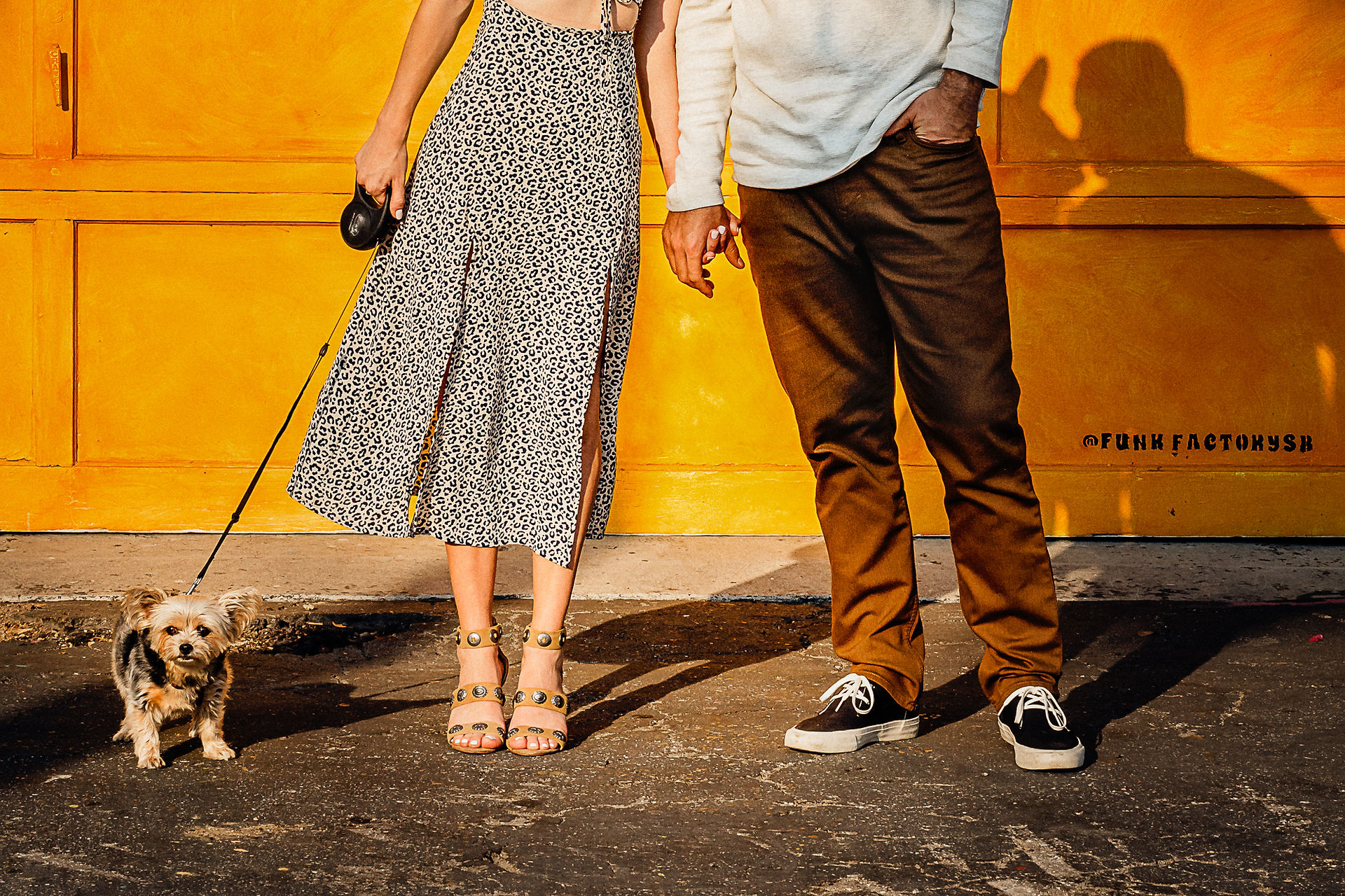 close up of couple and their yorkie dog, standing in front of yellow garage door