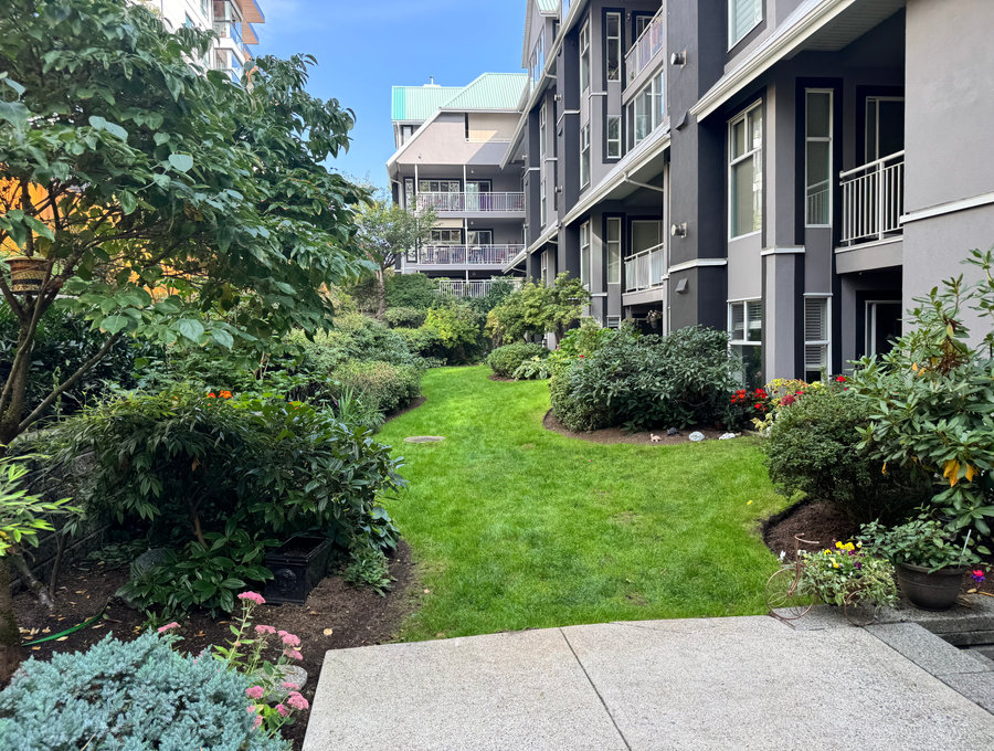 Shrub beds and lawn running alongside a mid rise residential building