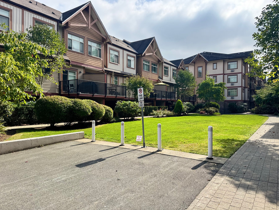 Open green and trimmed hedging in front of a townhome complex
