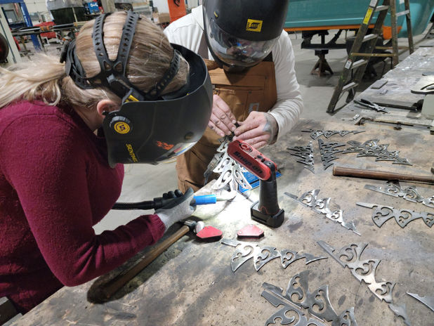 A close-up of a welder's hand at work on a metal project at Weld & Wine.