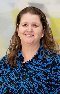 Woman with sandy brown hair, wearing a blue top, smiling.
