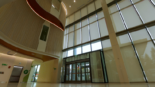 automated shades raising and lowering, covering multi-level windows in a hospital lobby