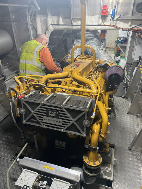 man in hi vis vest working on a yellow piece of machinery 