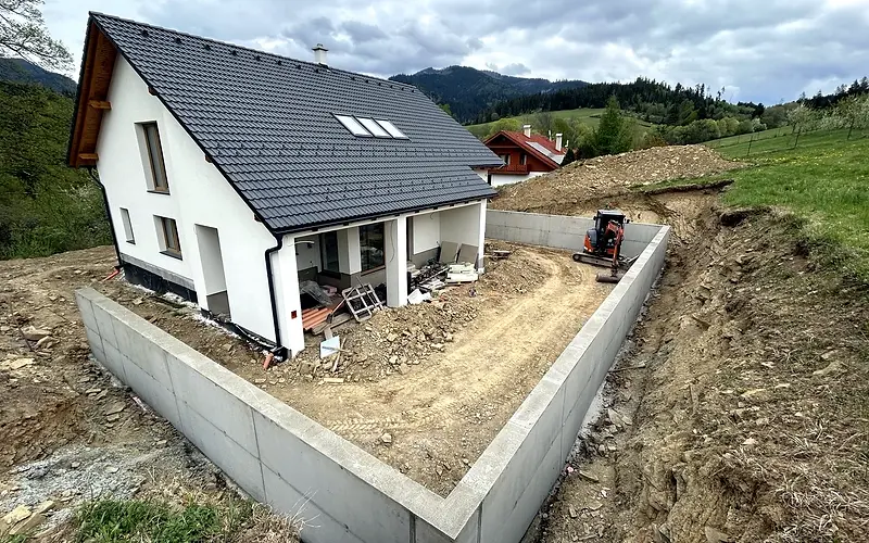 Dokončený betónový oporný múr okolo rodinného domu na svahovitom pozemku