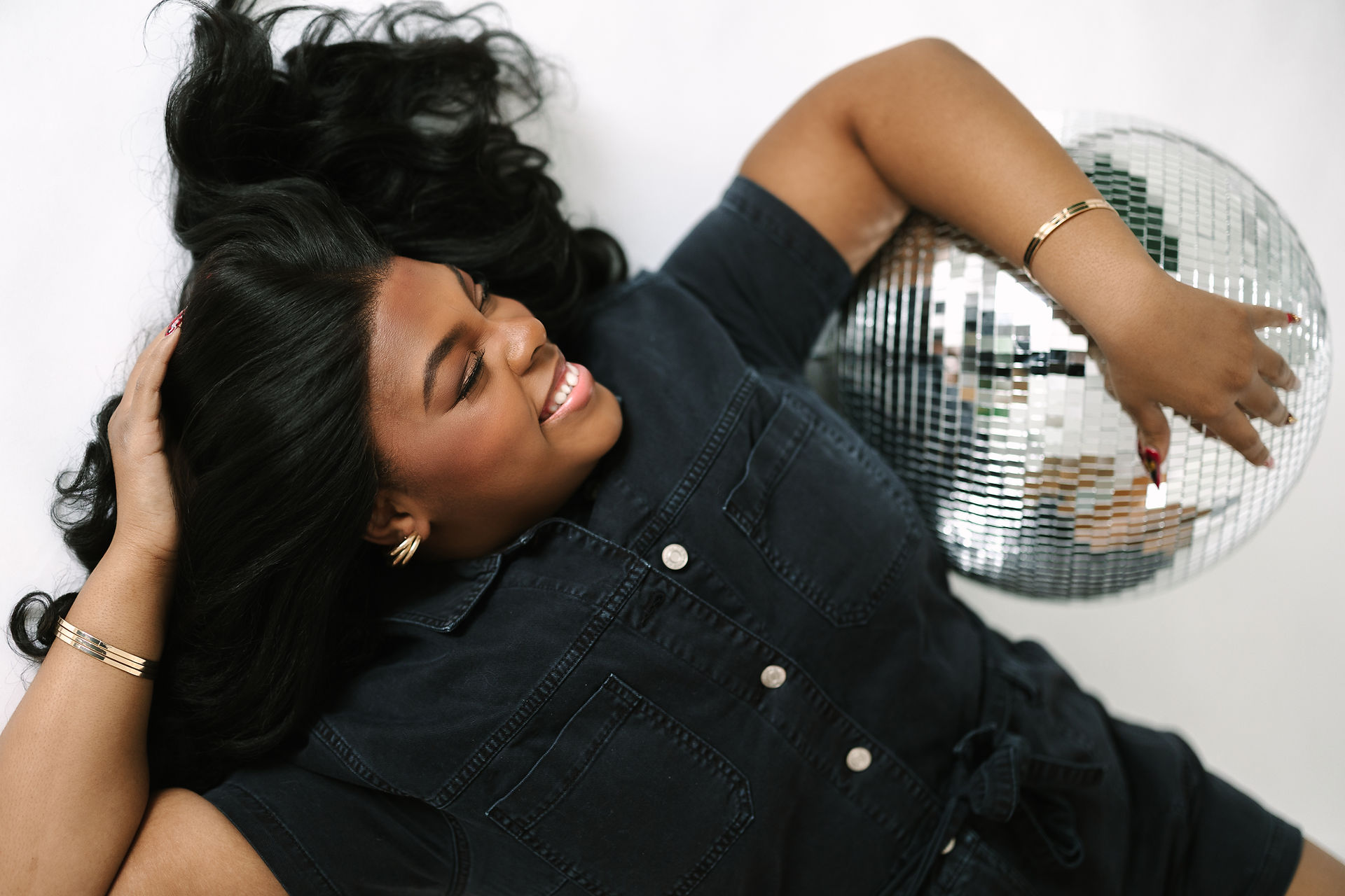 A candid moment of laughter while the client poses with a disco ball in my photo studio in Wixom, MI