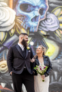 Couple laughing together in front of colorful murals during engagement photos at Eastern Market Detroit