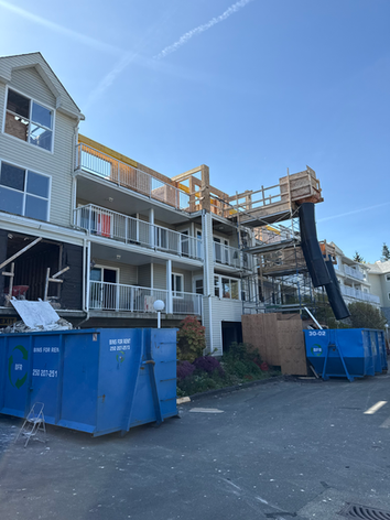 Home renovation with blue roll-off dumpsters and debris chute.