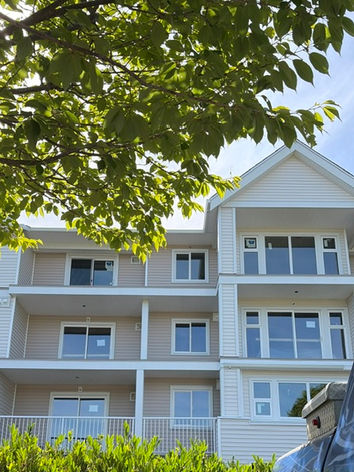 Modern white apartment building with balconies and trees.