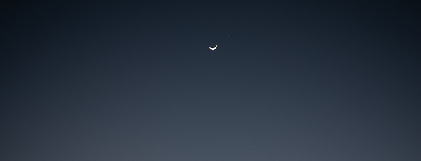 paisaje en el que se ve el atardecer y una luna incipiente en el cielo