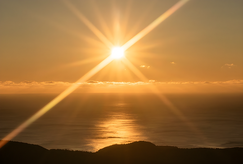 Sun set over the sea, with hills in the foreground