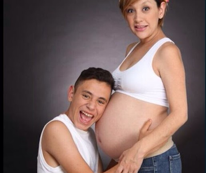 Hombre abrazando vientre de mujer embarazada, conexión emocional y diseño consciente.
