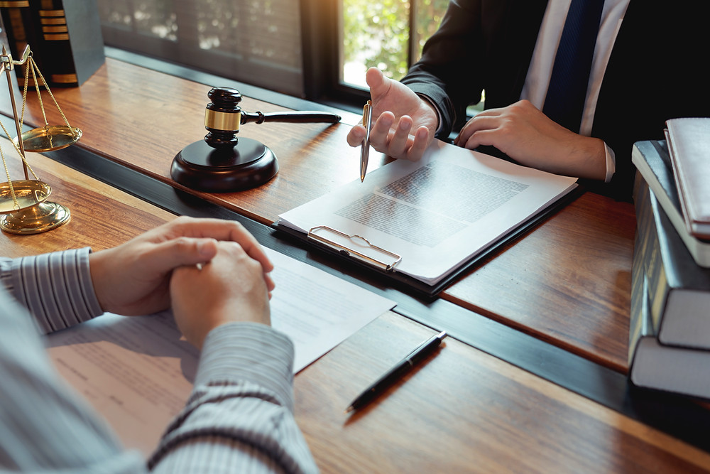 two people sitting at a desk with paperwork and a gavel right next to them