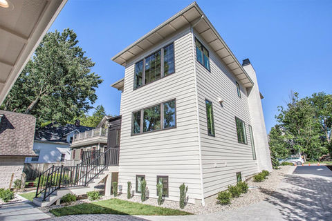 Modern light-colored multi-story house with horizontal siding under blue sky.
