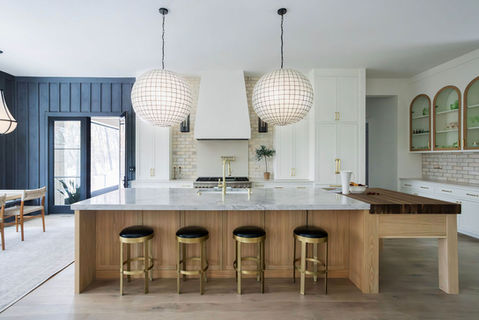 Modern kitchen island with brass stools and pendant lights