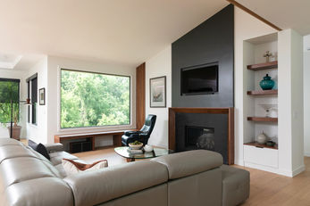 Modern living room with forest view, sofa, and fireplace