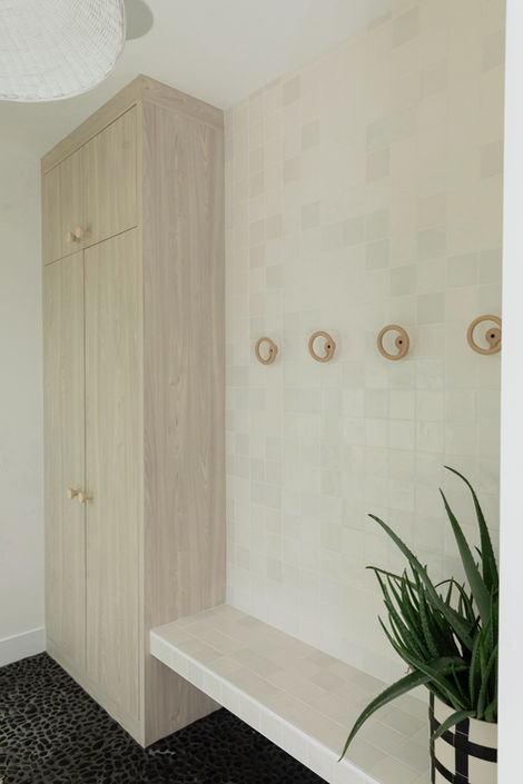 Modern entryway featuring light wood cabinet, floating bench, and stylish wall hooks.