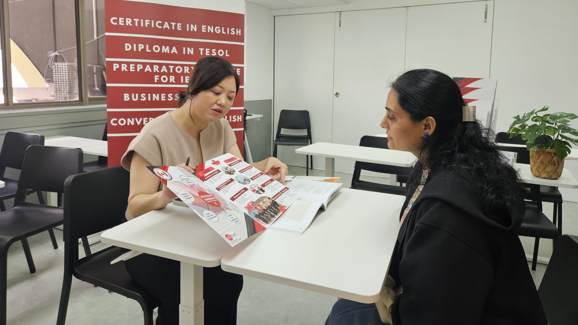 CEC staff member handing brochures to a family at the International Education Fair 2025 booth