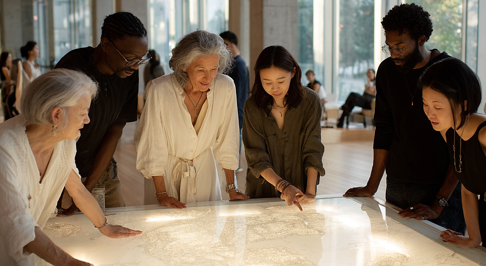A diverse group of six adults in a Seum, studying an interactive map, possible with funding