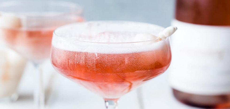 Close-up of two pink cocktails in coupe glasses with lychee garnish. Frosty glasses on a light background, exuding a refreshing, elegant vibe.