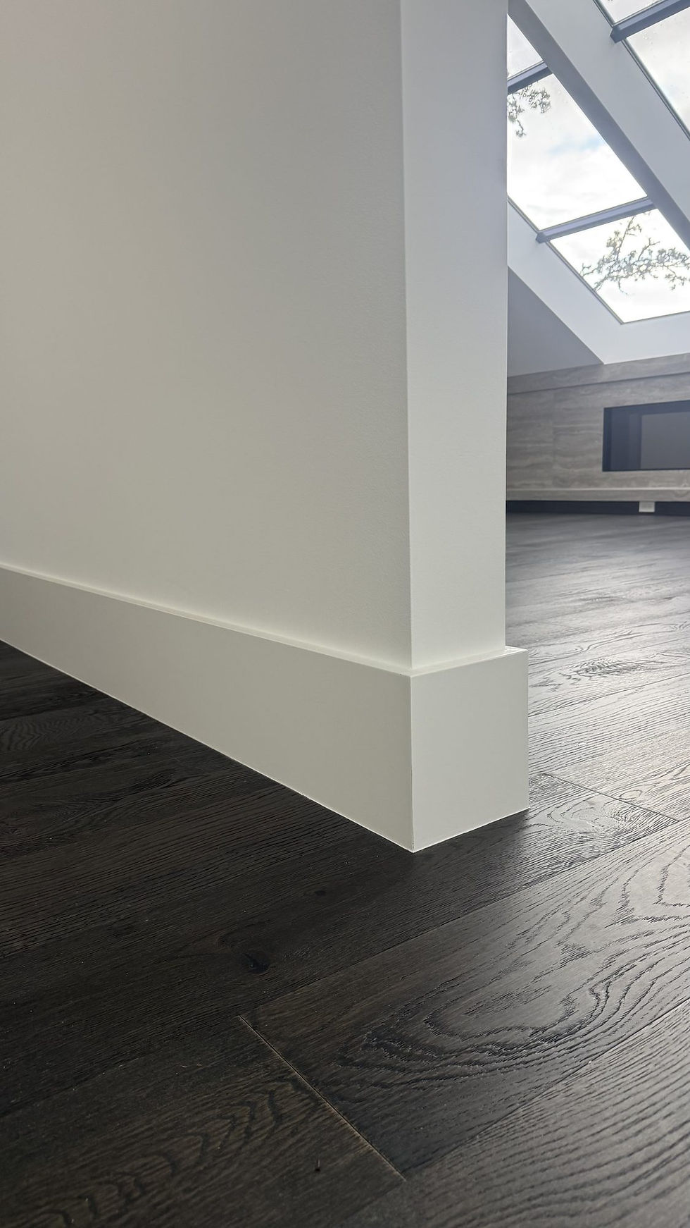 Skylight above a smooth white wall and dark floor
