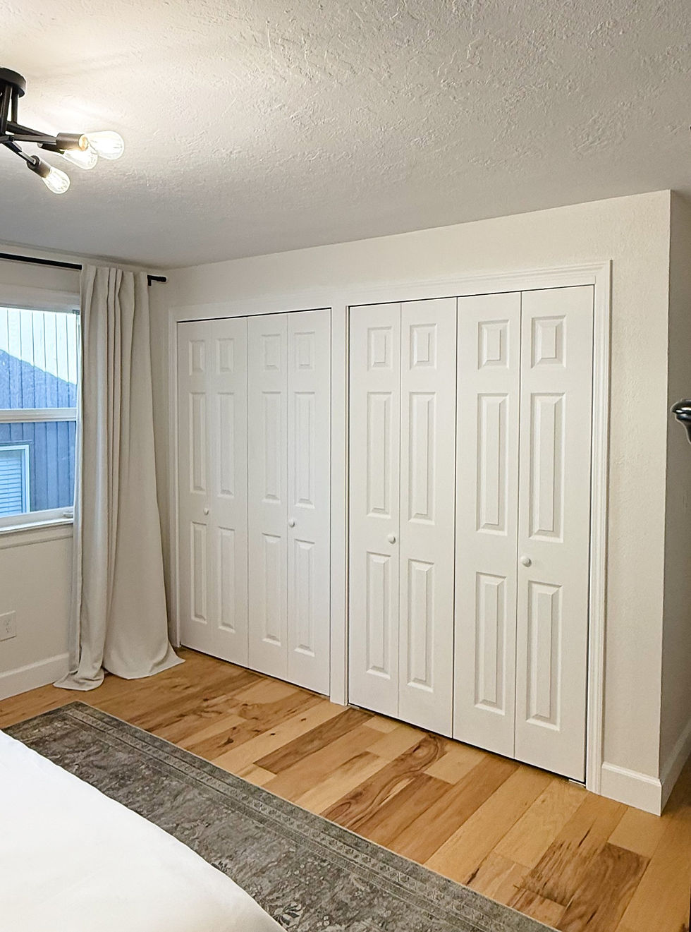 Bedroom with white painted closet doors, baseboards and new hardwood floor