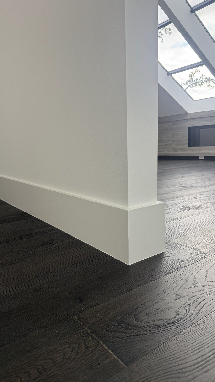 New white baseboards installed along a dark wood floor, Vancouver WA