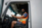 Man sitting in semi truck seat looking at camera