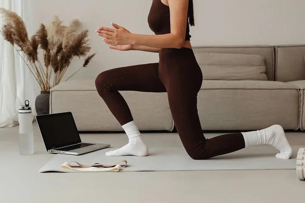 Woman with fibromyalgia in brown workout clothing kneels on a yoga mat beside a laptop and water bottle. Set in a cozy space with pampas grass and a beige couch, this scene reflects a home-based gentle movement routine for fibromyalgia symptom relief.