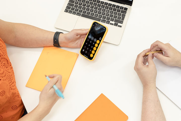 Orange notepad and calculator shown on phone held in a hand, pen poised