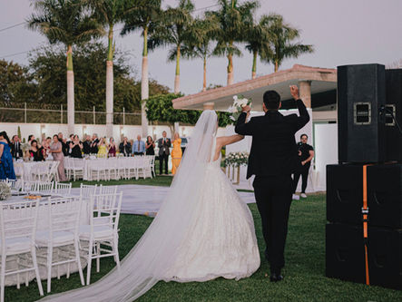 A newlywed couple entering reception area with live music