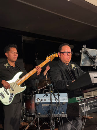 The AC Project performing live on stage at a wedding with bass and keyboards.