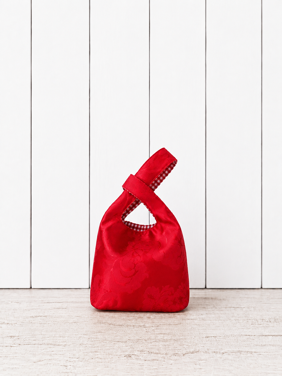 Sac Knot Bag rouge fait main en tissu satiné à motifs avec détails vichy rouge et blanc.