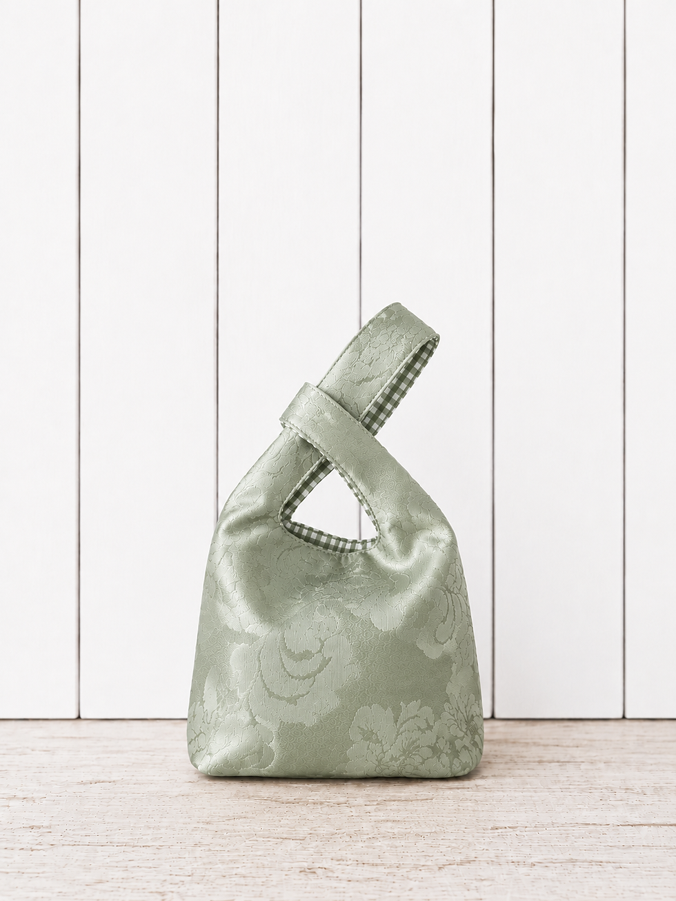 Sac Knot Bag vert sauge fait main en tissu satiné à motifs avec détails vichy vert et blanc.